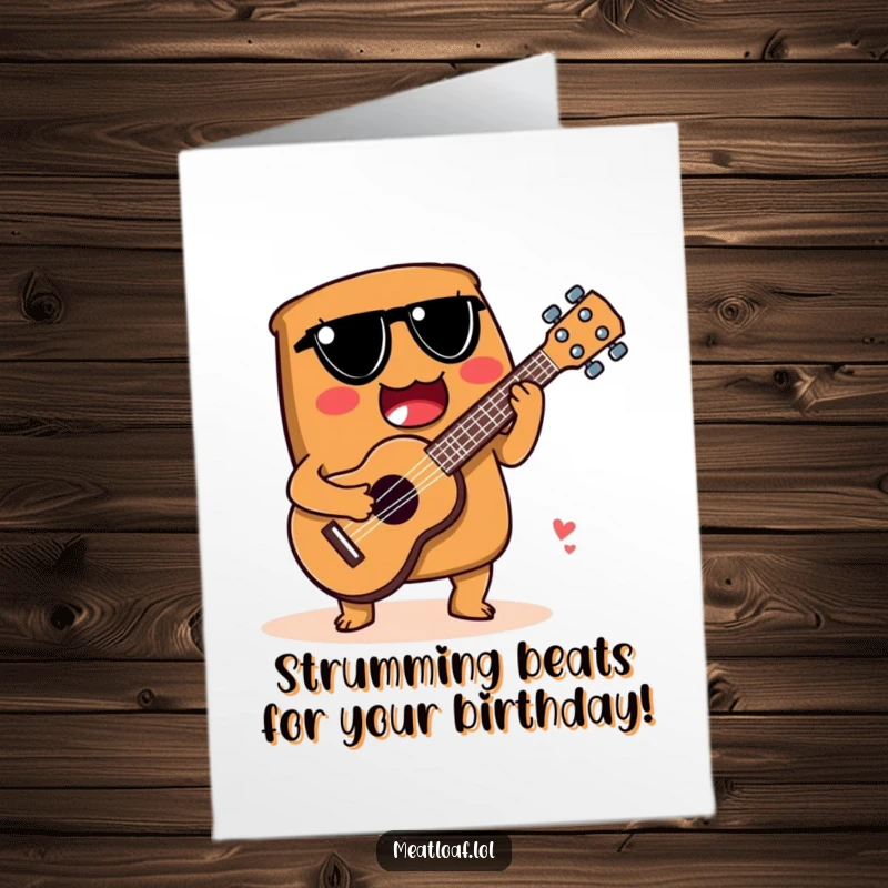 Funny Free Printable Birthday Card: A meatloaf character happily strums a ukulele crafted from a spoon, playing a birthday tune.